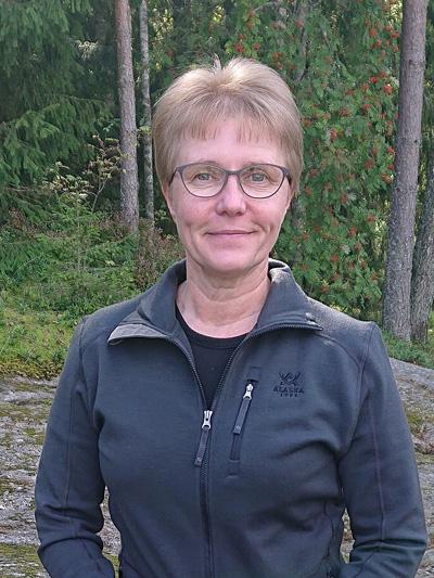 Maarit Piirtolan lähikuva, taustalla syksyistä metsää.