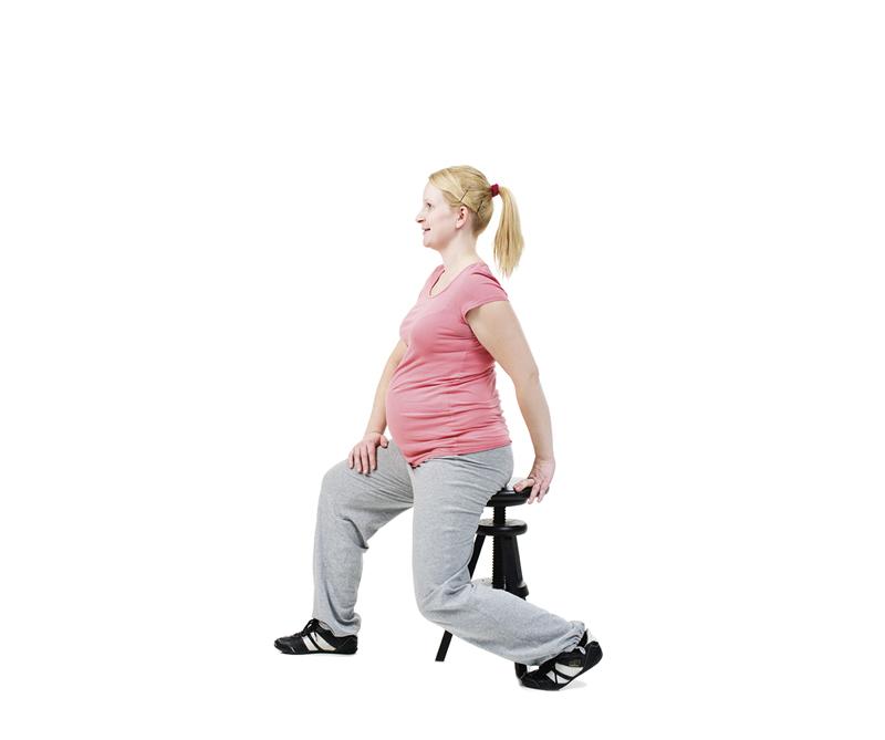 A pregnant woman is stretching her hip flexors.
