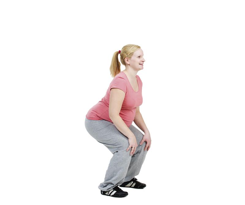 A pregnant woman is doing a squat.