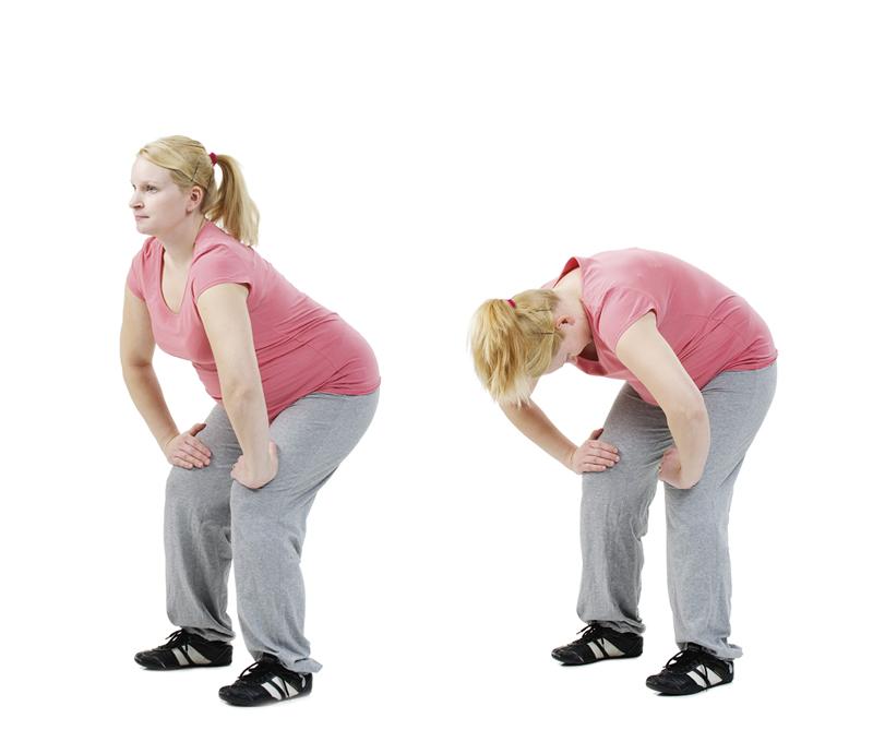 A pregnant woman is flexing and extending her back.